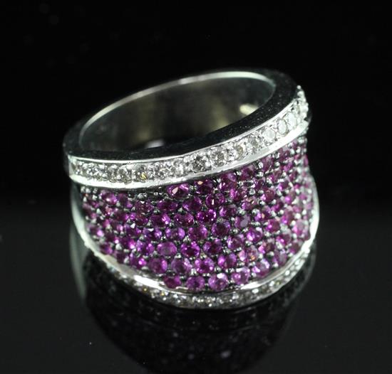 A modern white gold and pave set ruby dress ring with brilliant cut diamond set borders, size M.
